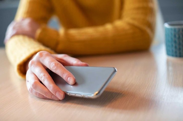 Woman Concerned About Excessive Use Of Social Media Laying Mobile Phone Down On Table