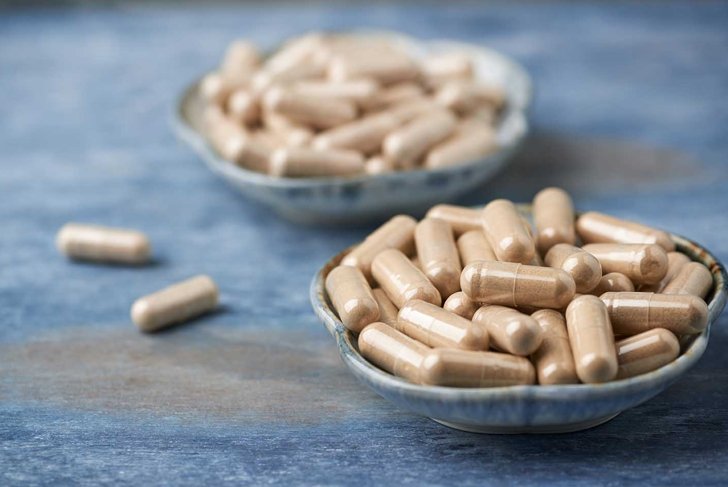 Ashwagandha (Withania somnifera) and Korean Ginseng capsules. Concept for a healthy dietary supplementation. Rustic wooden background. Copy space.